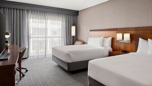 A hotel room with two beds, a desk, and a large window with curtains. - Courtyard by Marriott Detroit Livonia (Livonia)