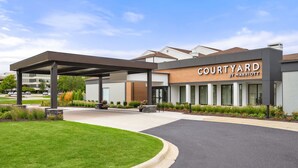 A Courtyard by Marriott hotel with a covered entrance, landscaped garden, and a clear sky. - Courtyard by Marriott Detroit Livonia (Livonia)