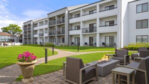 A modern apartment building with a courtyard featuring outdoor seating and a fire pit. - Courtyard by Marriott Detroit Livonia (Livonia)