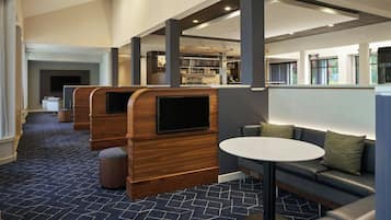 Een moderne lounge met houten wandpanelen, een ronde tafel en een televisiescherm.