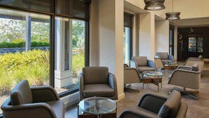 A modern lounge area with comfortable seating, large windows, and a bar area. - Courtyard San Francisco Larkspur Landing/Marin County (Larkspur)