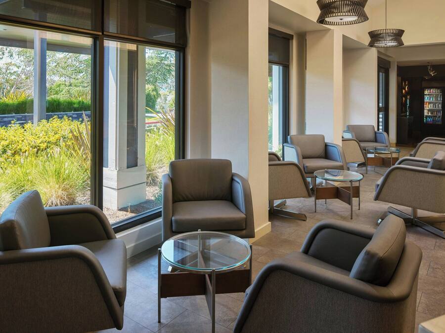 A modern lounge area with comfortable seating, large windows, and a bar area.