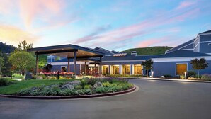 A modern hotel with a covered outdoor area, landscaped garden, and a view of the surrounding landscape. - Courtyard San Francisco Larkspur Landing/Marin County (Larkspur)