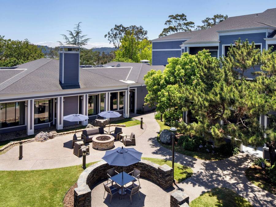 A courtyard with outdoor seating, a fire pit, and a covered area with a view of the surrounding landscape.