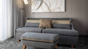 A modern living room with a grey sofa, a matching ottoman, and a floor lamp.