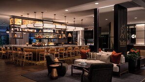 Un espace bar moderne doté d’un îlot central, de tabourets de bar et d’un coin salon avec des canapés et des fauteuils.