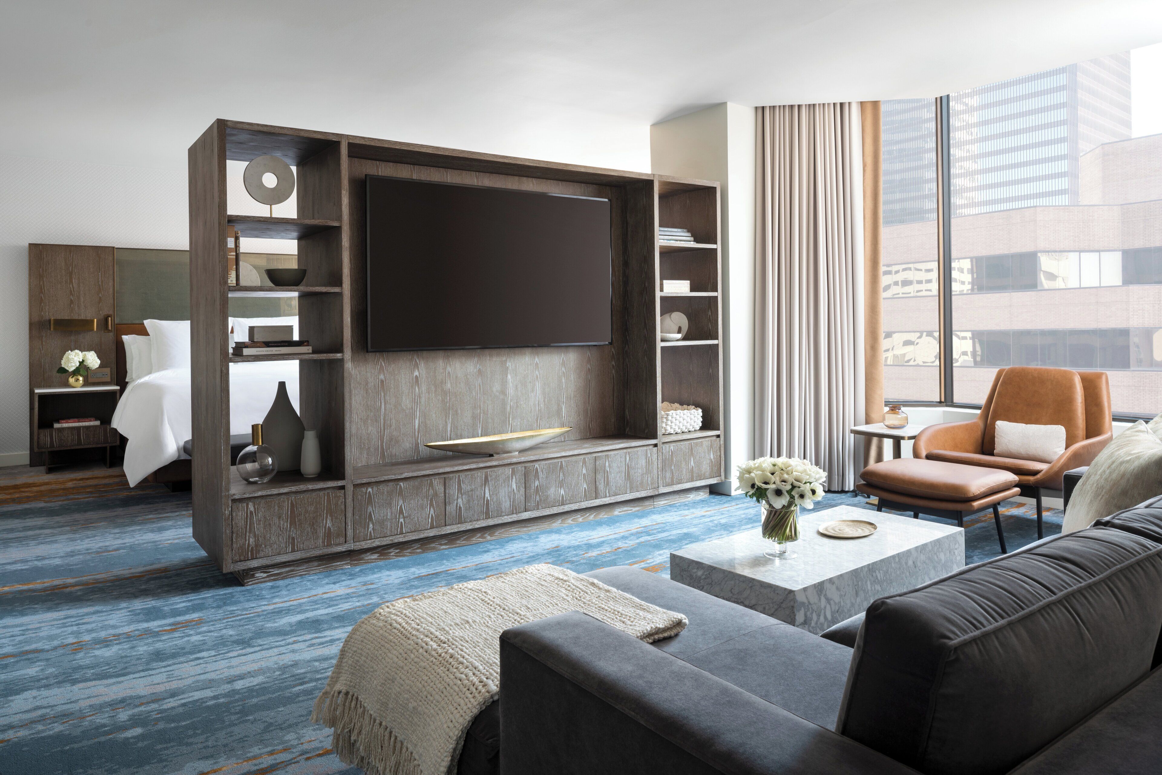 Habitació d'hotel moderna amb un televisor de pantalla plana gran, un sofà, una taula de cafè i una zona de seients amb una cadira.