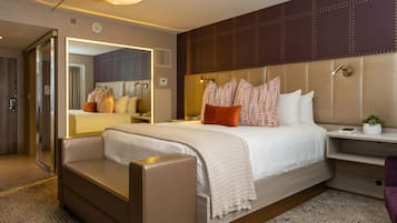 Una habitación de hotel moderna con una cama grande, una zona de estar, un tocador y un espejo.