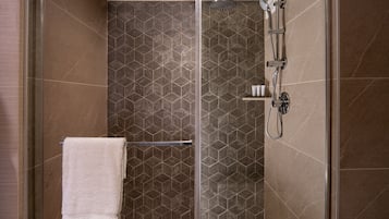 A walk-in shower with a glass door, a towel rack, and a showerhead.