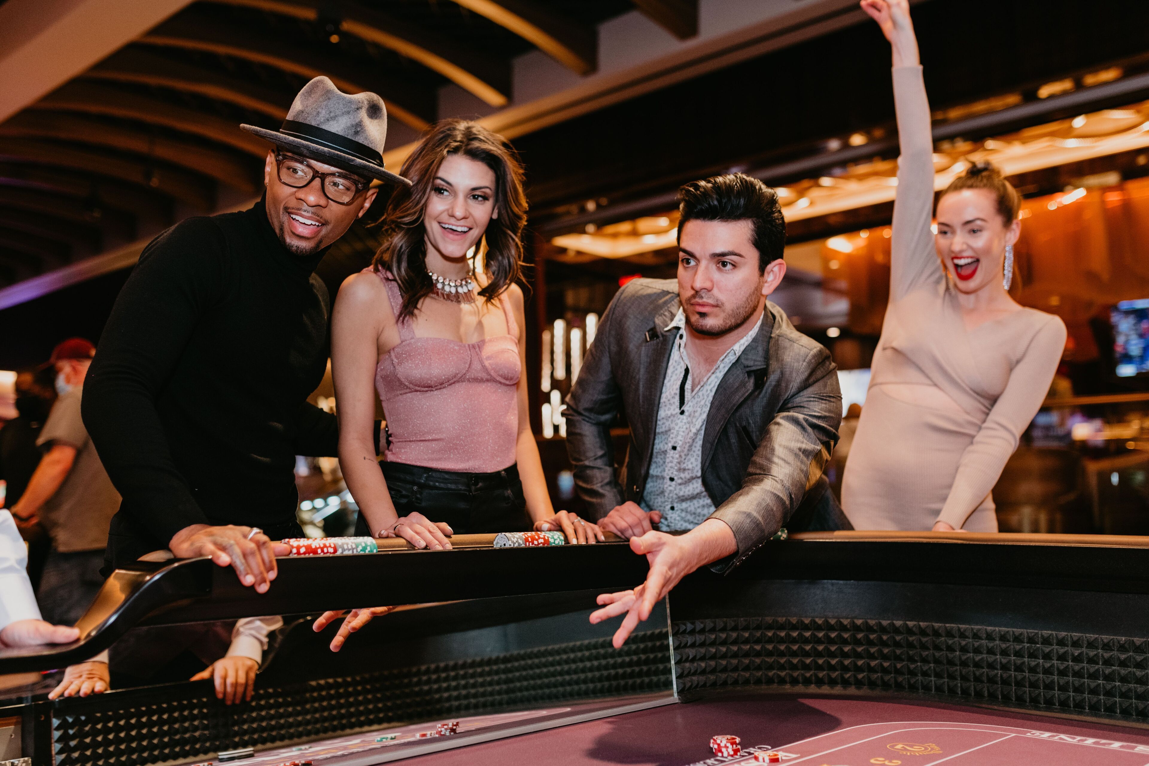 Un grupo de personas jugando en una mesa de craps en un casino, con una ruleta y fichas a la vista.