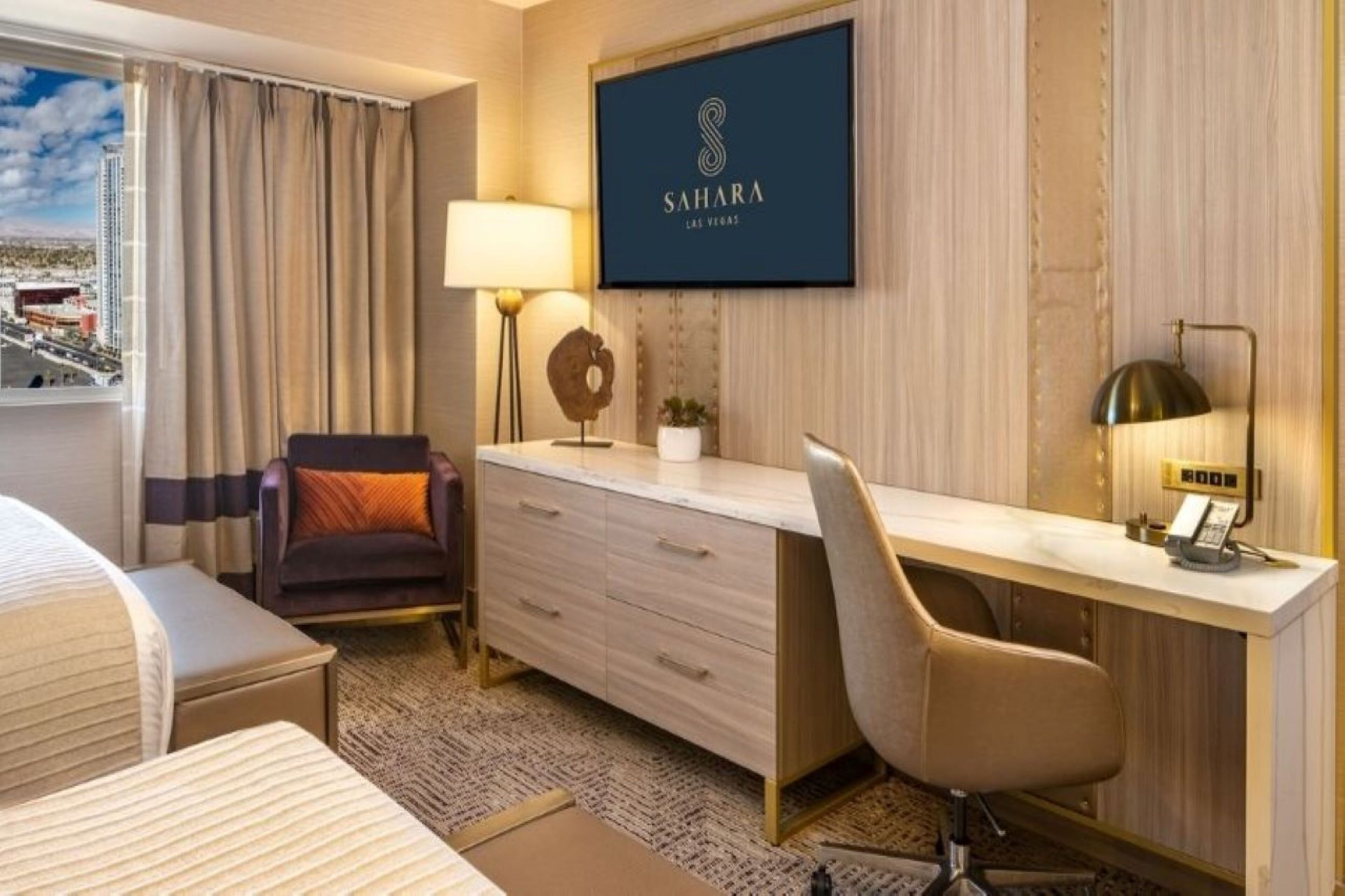 Une chambre d’hôtel avec un lit, un bureau, une chaise, une lampe et une vue sur la ville.
