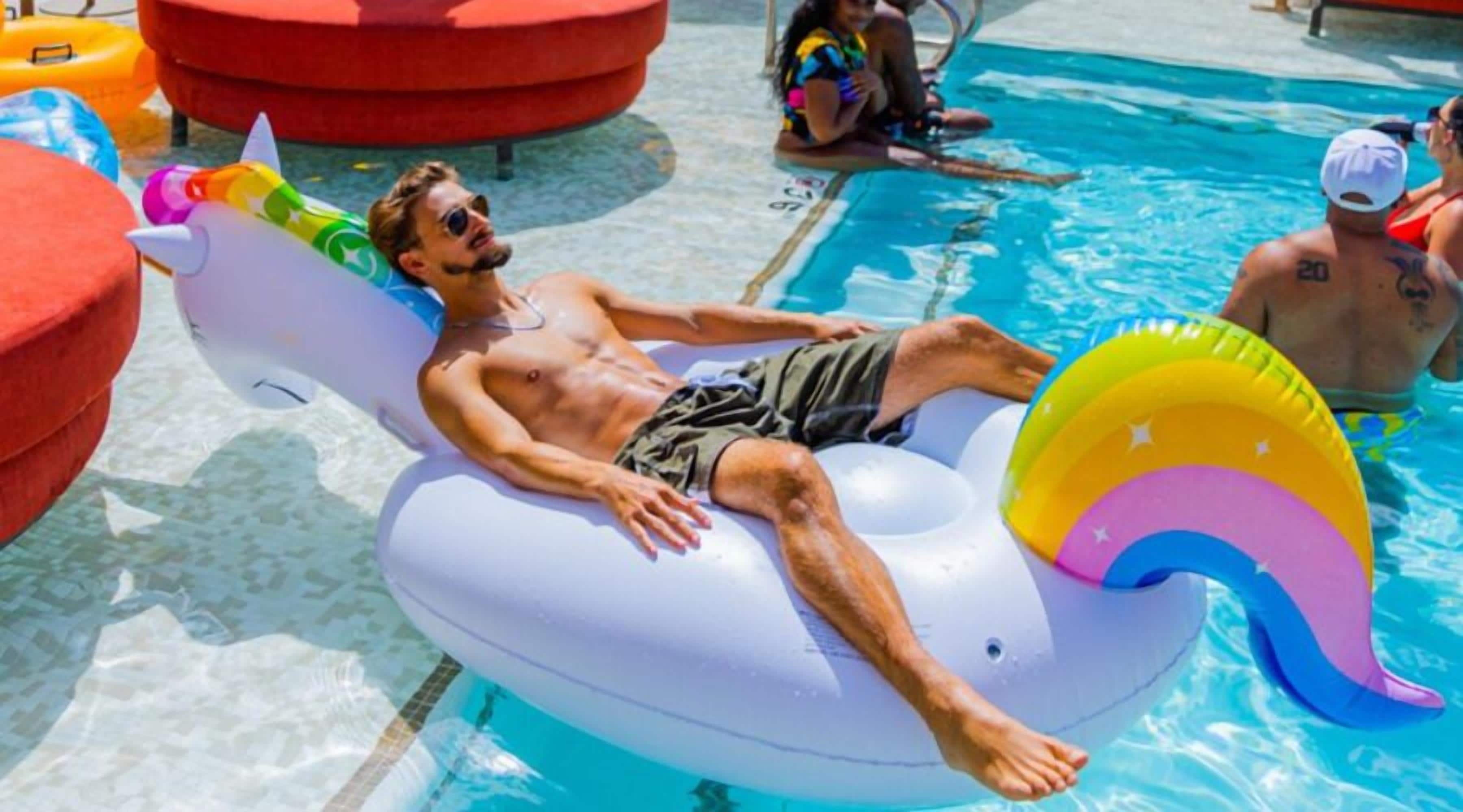 Un hombre recostado sobre un flotador colorido en una piscina.