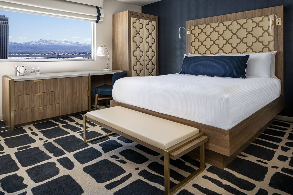 A hotel room with a large bed, a desk, and a view of mountains.