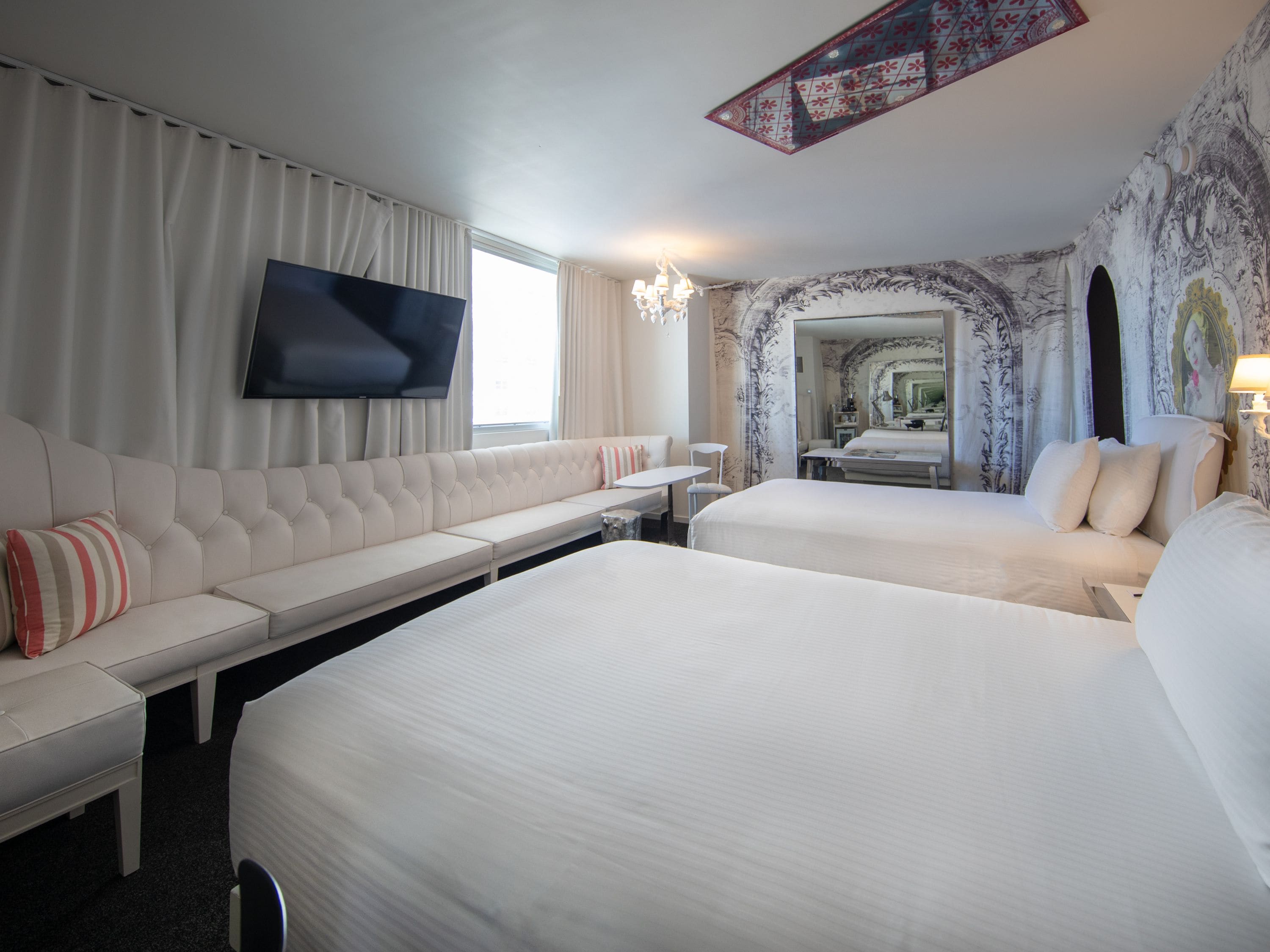 Una habitación de hotel con una cama grande, un sofá, un televisor y un espejo.
