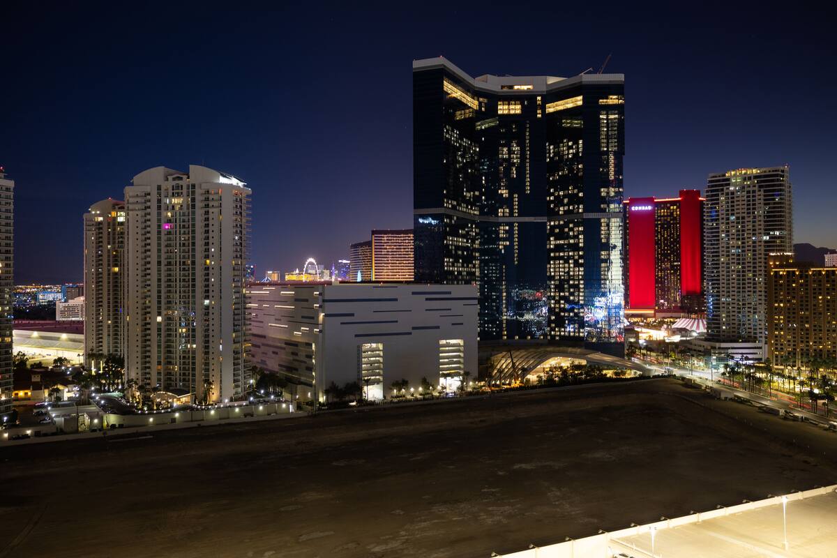 A nighttime cityscape with high-rise buildings, including a prominent building with a red-lit facade.