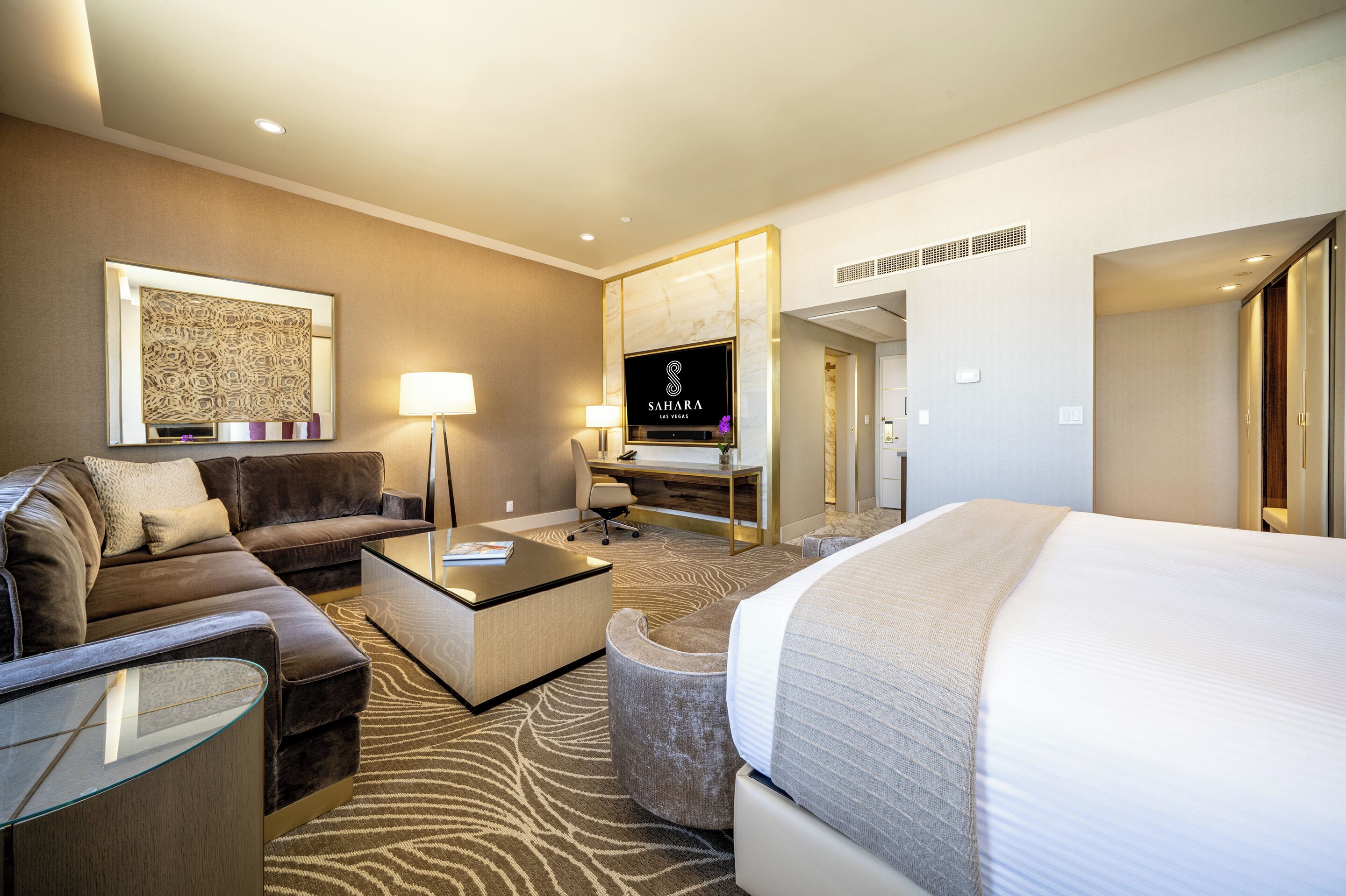 Une chambre d’hôtel avec un lit, un canapé, un bureau et une télévision.