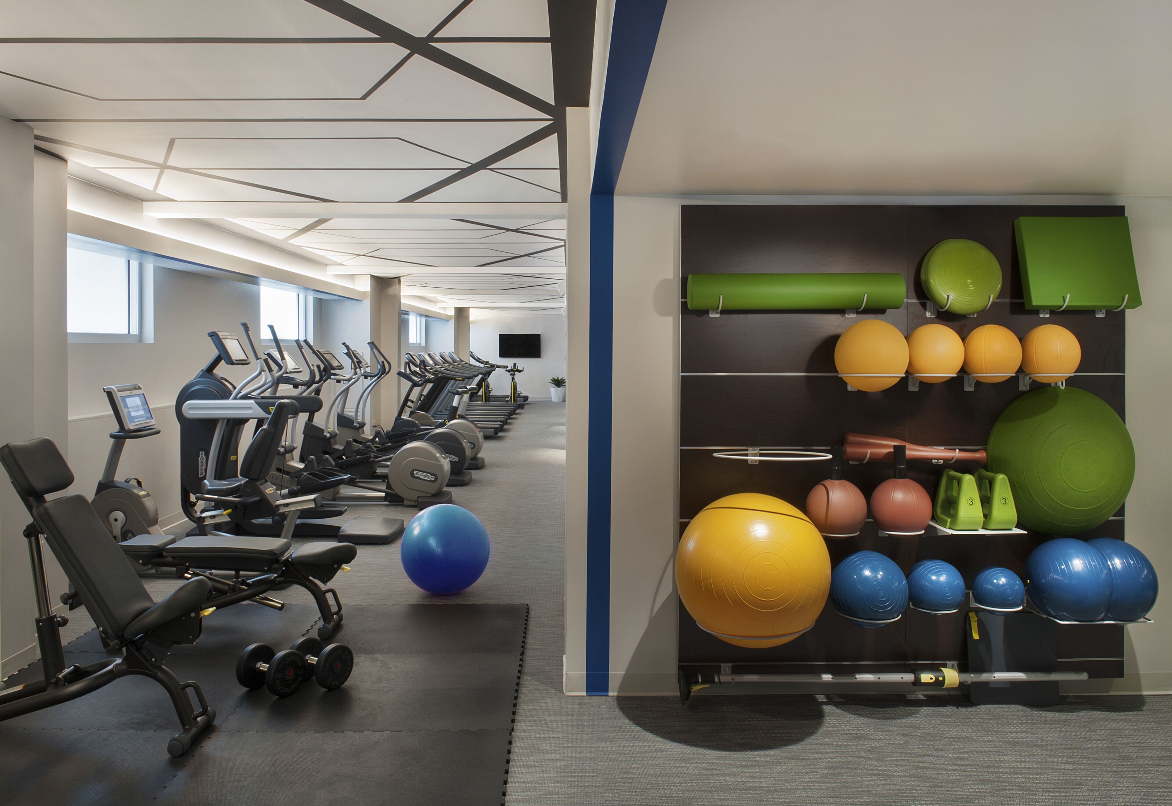 Una palestra con tapis roulant, macchinari per pesi e diversi tipi di palle per esercizi.