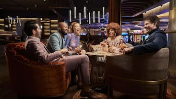 A group of people seated around a round table in a well-lit indoor setting with modern decor and ambient lighting.