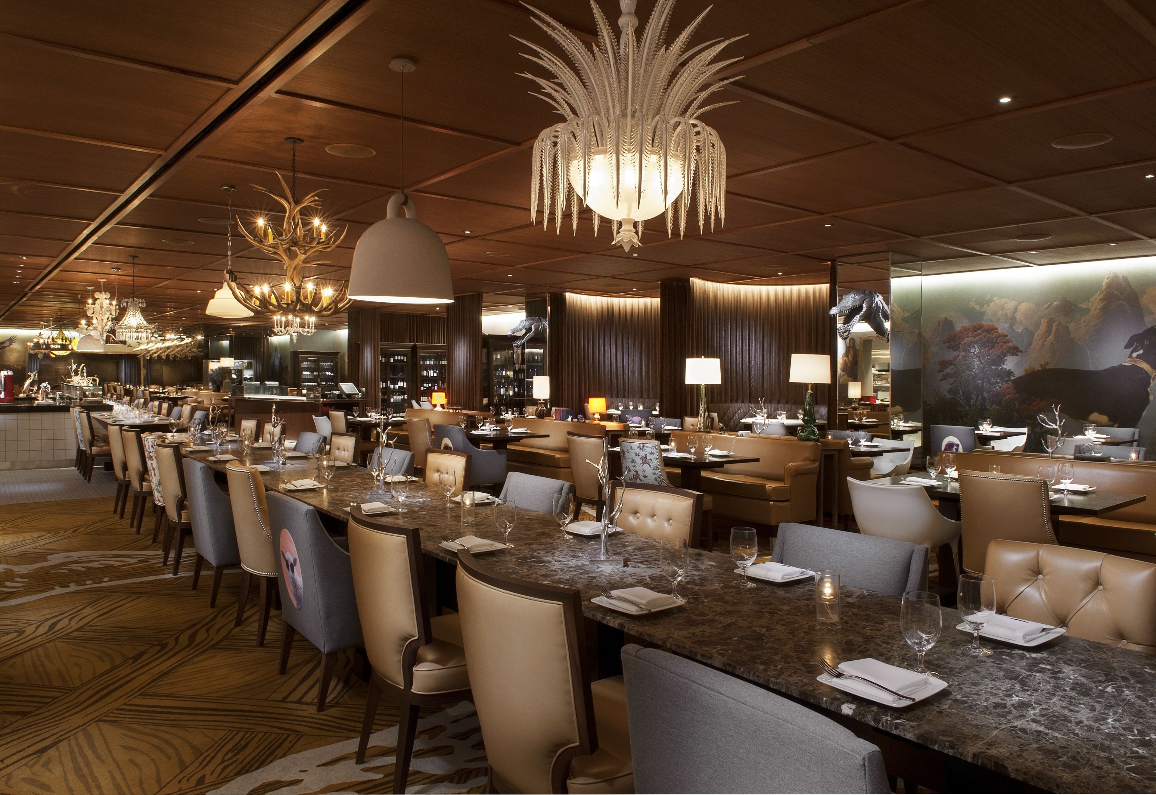 Un restaurante espacioso con varias mesas, candelabros elegantes y un ambiente cálido.