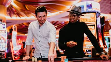 Un entorno de casino con una ruleta y máquinas tragamonedas.