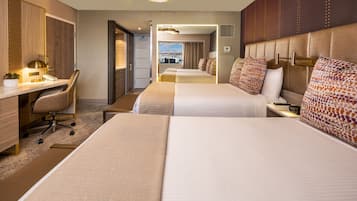 Ein Hotelzimmer mit zwei Betten, einem Schreibtisch, einem Stuhl und Blick auf die Stadt.