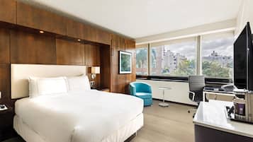 A hotel room with a large bed, a desk, a chair, and a TV.