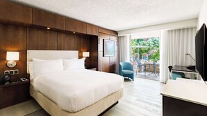 A hotel room with a large bed, a desk, a chair, and a view of the outdoors. - DoubleTree by Hilton San Juan (San Juan)