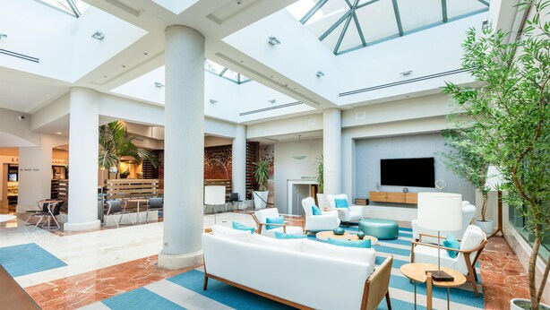 A spacious lobby with a high ceiling, large windows, and a seating area with sofas and chairs. - DoubleTree by Hilton San Juan (San Juan)