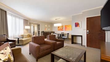 Habitación de hotel con sala de estar, mesa de comedor y cocina.
