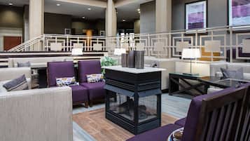 A modern lobby with sofas, armchairs, and a fireplace.