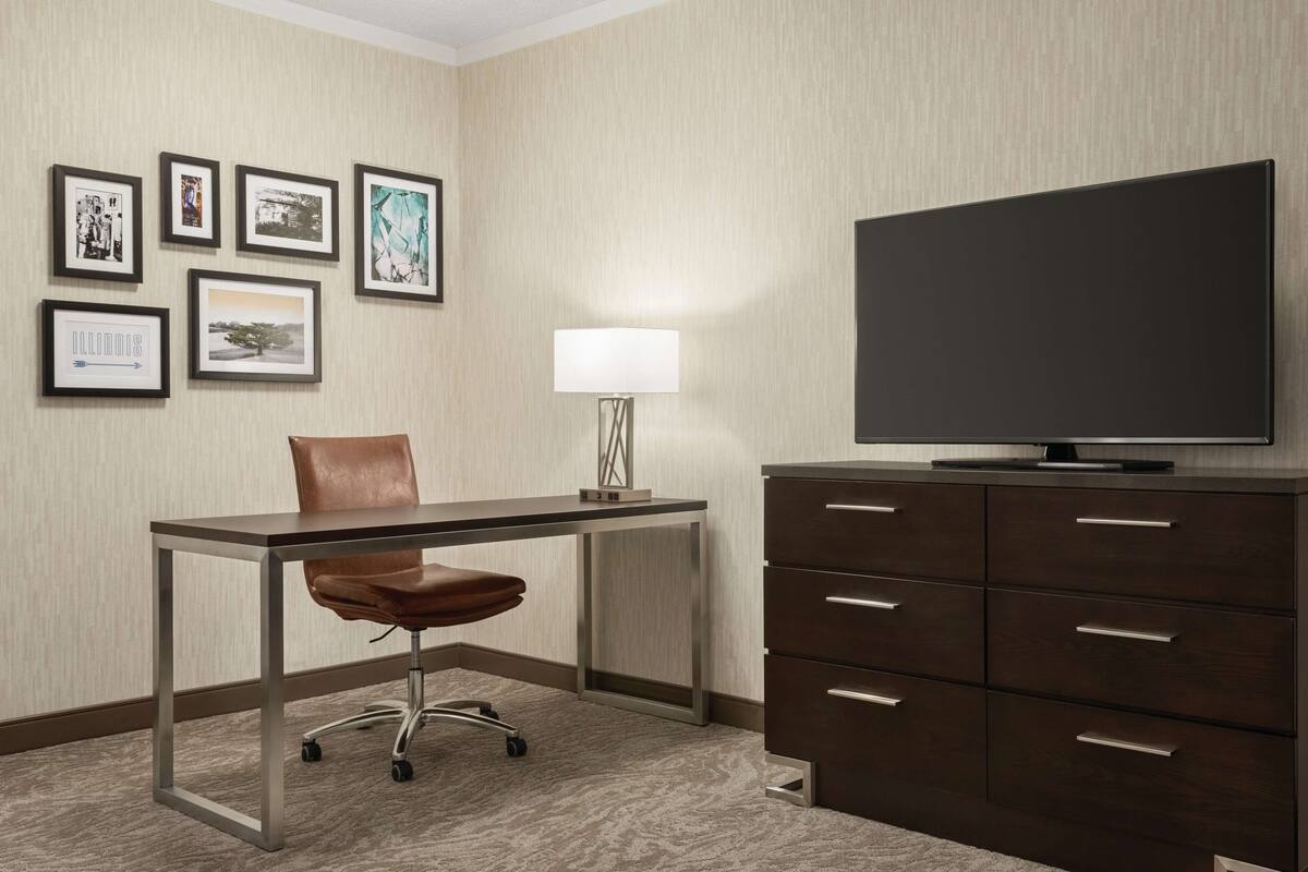 Une chambre d’hôtel équipée d’un bureau, d’une chaise, d’une télévision et d’une lampe.
