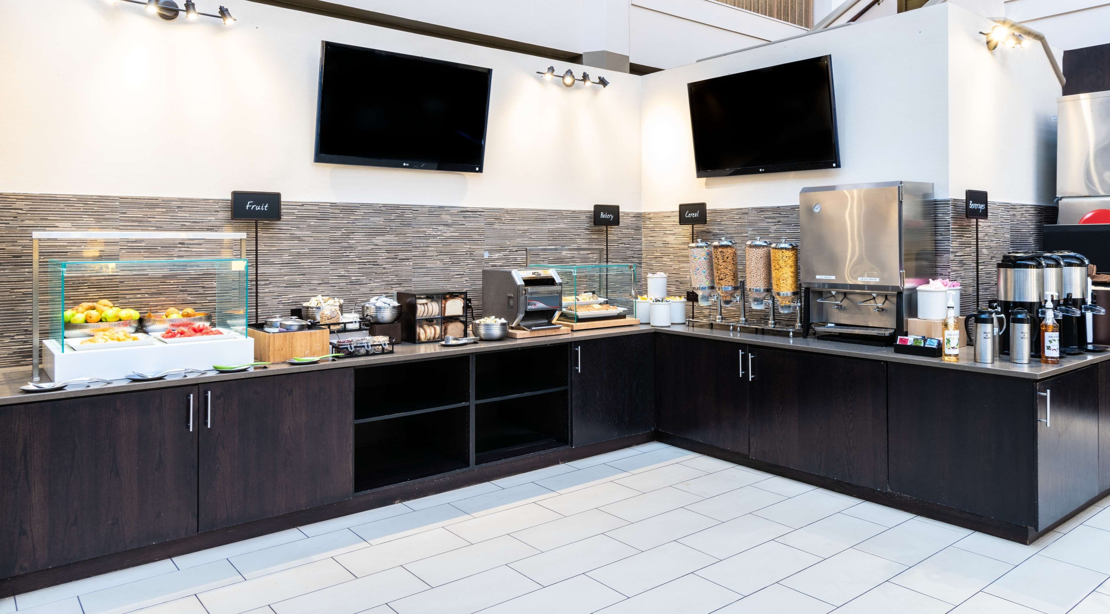 A modern breakfast bar with a variety of food options, including fruit, cereal, and beverages, and a coffee station.