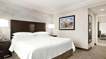 Una habitación de hotel con una cama grande, una mesita de noche, una lámpara y un cuadro enmarcado en la pared.
