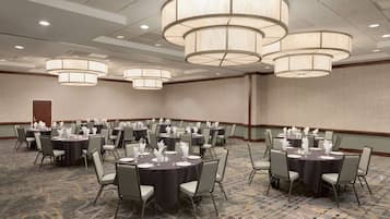 A conference room with multiple tables set for a meeting, equipped with chairs and tables, and large ceiling lights.