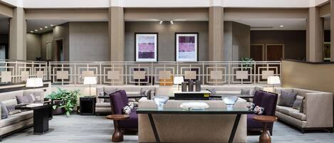 A spacious lobby with a central seating area, multiple sofas, and a glass-top table.