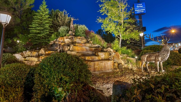 A landscaped area with a deer statue, a waterfall, and signs for Best Western and a Legal Tender Restaurant Lounge. - Best Western Dunmar Inn (Evanston)