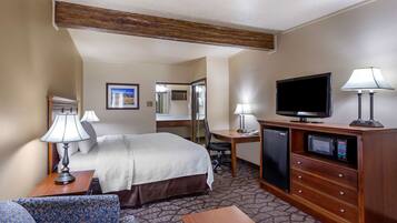 A hotel room with a bed, desk, television, and a sofa.