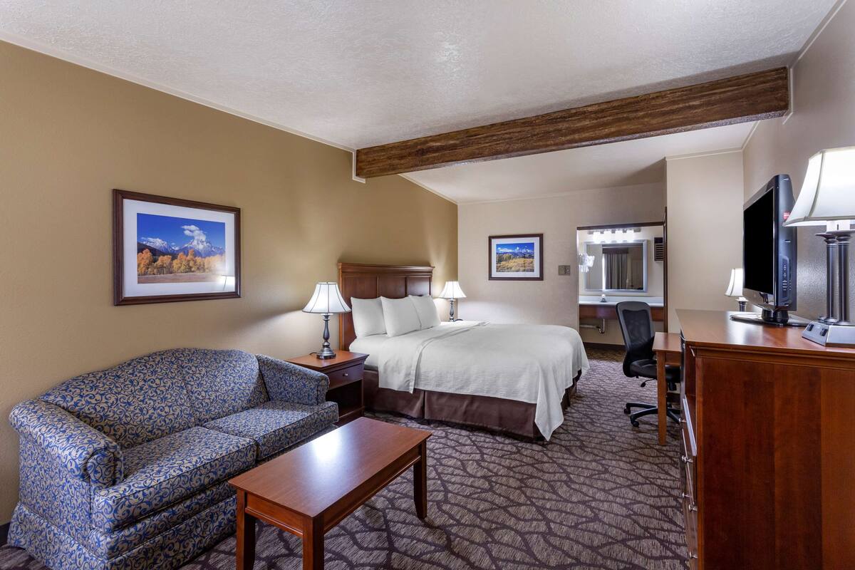 Ein Hotelzimmer mit Sofa, Bett, Schreibtisch und Fernseher.