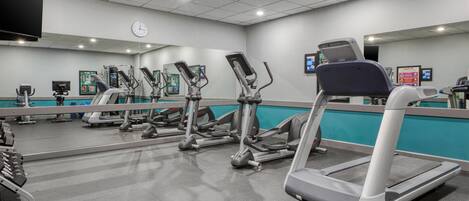 A gym with multiple treadmills, elliptical machines, and weight benches.