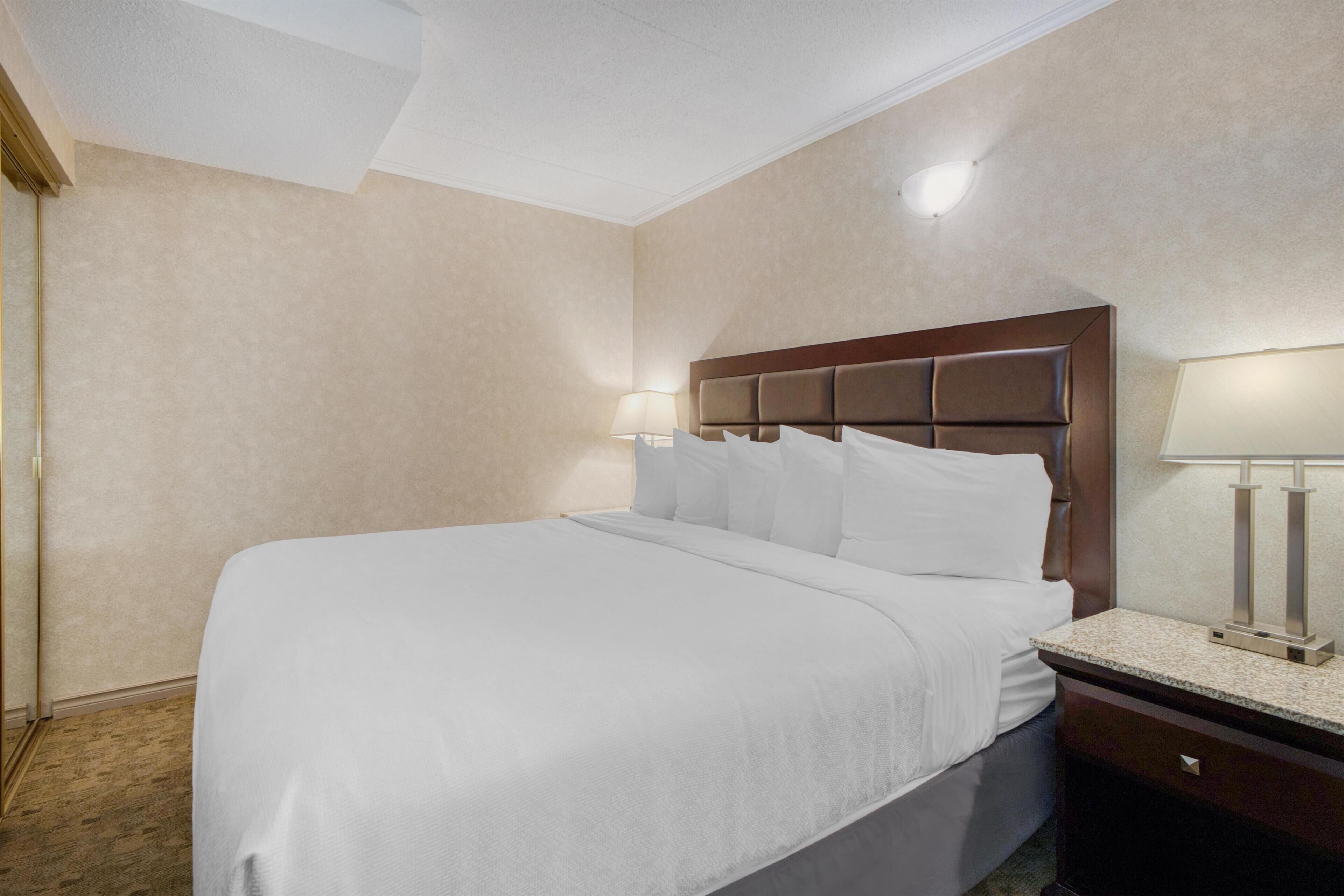 Habitación de hotel con una cama grande, una mesita de noche con lámpara y un aplique de pared.
