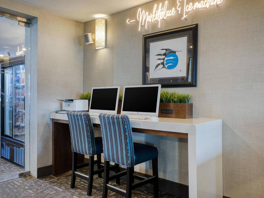 En hotellreception med två datorskärmar, ett inramat konstverk och en neonskylt.