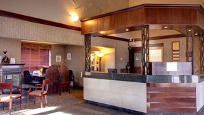 A reception area with a marble counter, wooden chairs, and a desk with a computer. - Best Western Plus City Centre Inn (Edmonton)