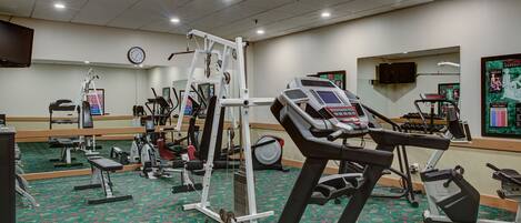 A gym with treadmills, weight machines, and a mirrored wall.