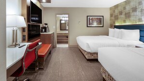 A hotel room with a bed, a TV, a desk with a chair, and a bathroom visible through an open door. - Best Western Plus City Centre Inn (Edmonton)