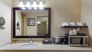 A bathroom with a large mirror, a sink, a coffee maker, a microwave, and a shelf with towels. - Best Western Plus City Centre Inn (Edmonton)