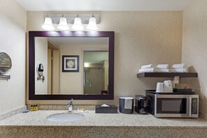 A bathroom with a large mirror, a sink, a coffee maker, a microwave, and a shelf with towels. - Best Western Plus City Centre Inn (Edmonton)