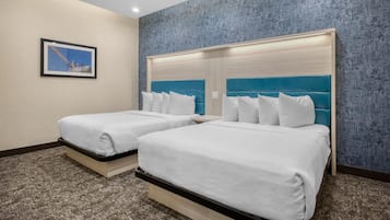 A hotel room with two beds, a cityscape wallpaper, and a framed picture on the wall.