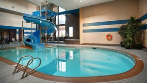 An indoor swimming pool with a blue water slide, a lifebuoy, and potted plants. - Best Western Plus City Centre Inn (Edmonton)