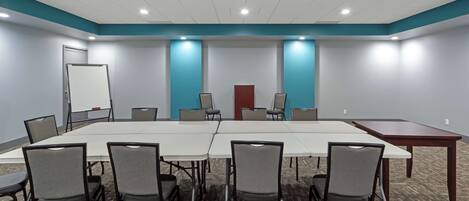 Un salón de conferencias con una mesa larga, seis sillas y una pizarra.