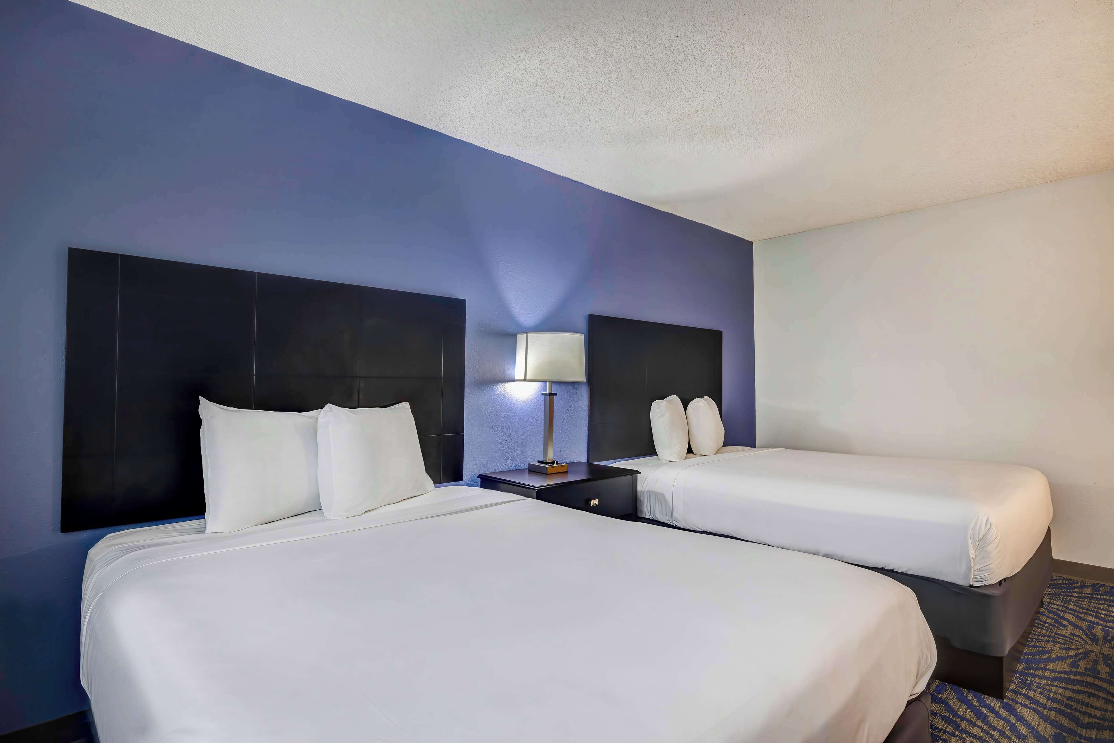 Ein Hotelzimmer mit zwei Betten, einem Nachttisch mit Lampe und einer blauen Wand.